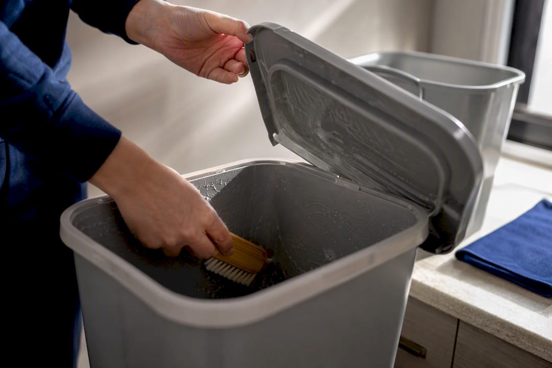 Hands washing an indoor recycling container